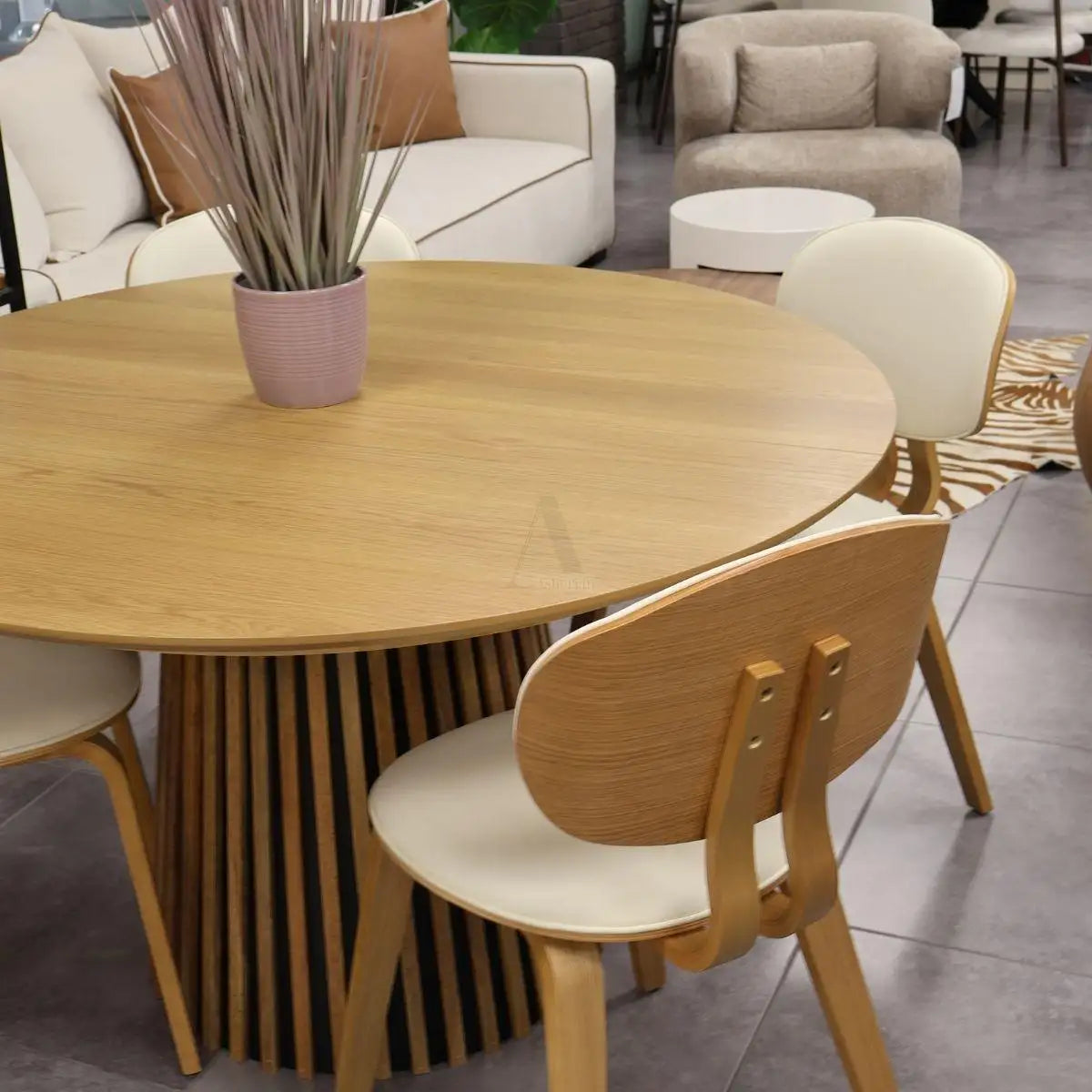 שולחן אוכל עגול מעץ בהיר עם בסיס מחלולי וכיסאות תואמים